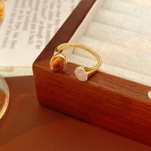 Détail d'une bague dorée avec œil de tigre et cristaux sur un coffret en bois