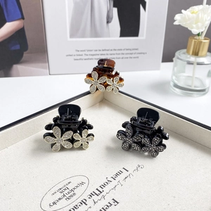 Detail of floral hair claws with rhinestones in amber and black on a jewelry display box