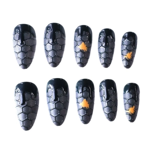 Long almond press-on nails with black honeycomb texture and yellow drip design