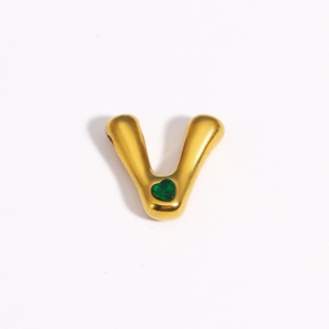 Détail du pendentif doré en forme de V serti d'une pierre précieuse cœur verte