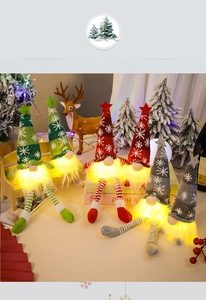 Three glowing Christmas gnomes with LED lights, knitted hats, and long legs on a festive desk