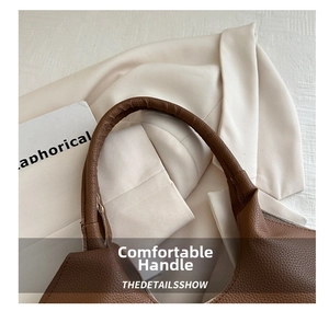 Detailed macro view of the brown leather handle with premium lychee grain texture