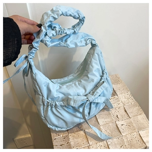 Close-up of light blue nylon pleated shoulder bag with bow detail and drawstring