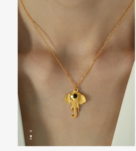 Detail of a gold elephant pendant necklace with black bead eye worn by a female model