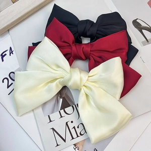 Detailed view of large satin bow hair clips in black, burgundy and beige colors