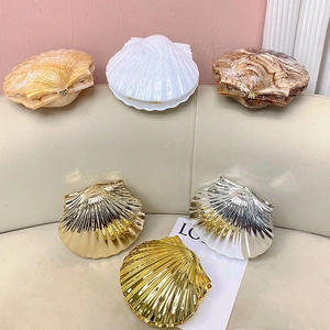 Détail de sacs de soirée en forme de coquille aux finitions marbre, perle et métal