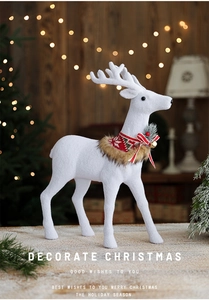 Close-up of a white Christmas reindeer figurine with red collar and golden bell details