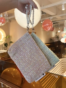 Detail of tweed makeup pouch with pearl handle and metallic clasp in soft warm lighting