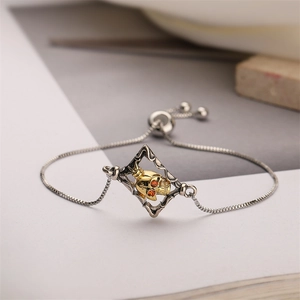 Detailed close-up of a punk skull bracelet with red rhinestone eyes and box chain