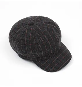Top view detail of dark gray wool newsboy cap with orange plaid patterns and texture