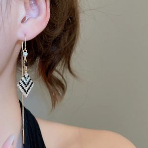 Détail d'une boucle d'oreille élégante à pendentif losange en diamant sur un modèle