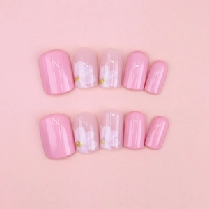 Faux ongles roses à presser avec motifs fleurs blanches et touches de paillettes dorées