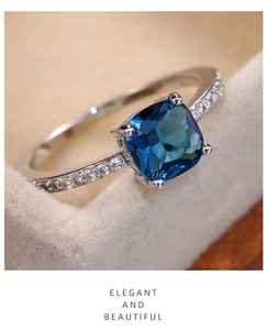 Macro shot of cushion cut blue sapphire ring with micro-pave diamonds in a gift box