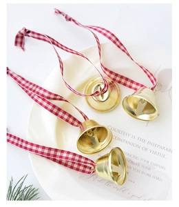 Close-up of golden metal Christmas bells with red plaid ribbons on a gift card