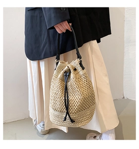 Straw bucket bag styled with a black blazer and pleated skirt on a model