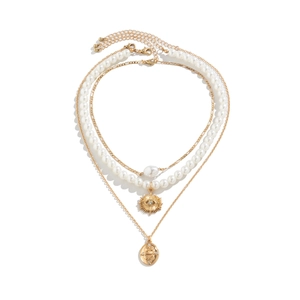 Detail of layered gold necklaces with faux pearls and vintage snake pattern pendants