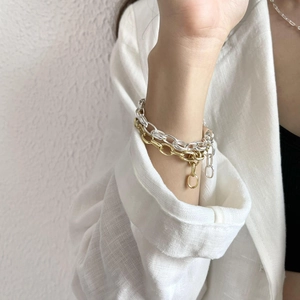 Detail of minimalist double-layer gold and silver mixed chain bracelet on model's wrist