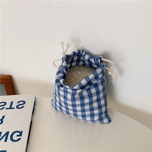 Blue and white plaid linen drawstring bag filled with grains on a minimalist white desk