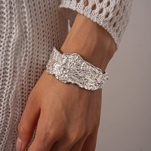 Detail of silver irregular crumpled texture cuff bracelet on model's wrist