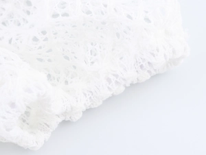 Close-up of white hollowed-out mesh fabric with elastic hem detail and knit texture