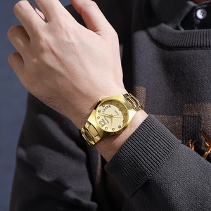 Close-up of golden quartz watch on wrist showing calendar window and crystal markers