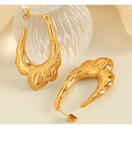 Detailed view of the 18K gold plated lava textured hollow hoop earrings on a textured surface