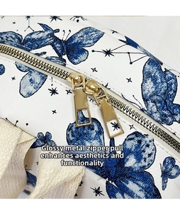 Detail of golden dual zippers and blue butterfly star print on white canvas backpack