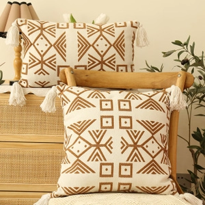 Detail of tufted boho cushion covers with geometric patterns and tassels on wooden furniture