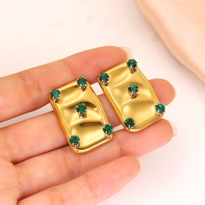 Detail showing rectangular gold-plated earrings with five green rhinestones in macro view
