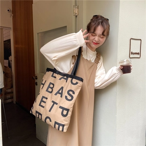 Close-up of khaki canvas tote bag with large black lettering on a café background