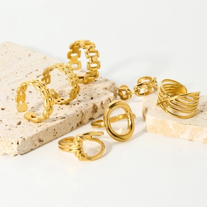 Ensemble de bagues géométriques en acier inoxydable plaqué or 18K sur un socle en pierre