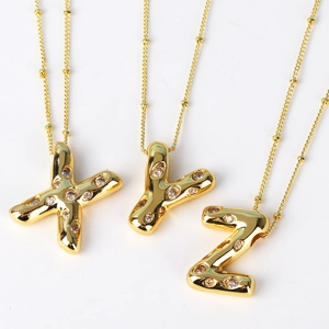 Close-up of gold-plated iced out X Y Z initial pendants with sparkling zircon stones
