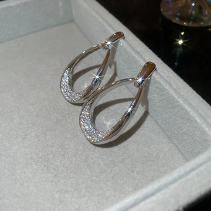 Close-up of silver teardrop earrings with shimmering crystals in a gray jewelry box
