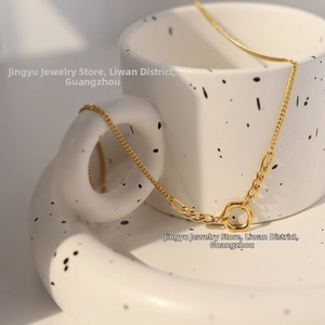 Detailed view of an 18K gold plated chain necklace with a hollow circle pendant