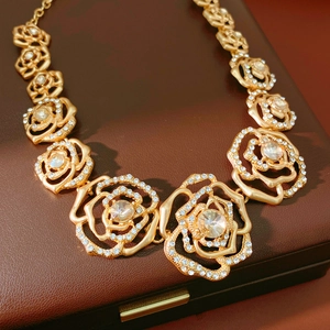 Detail of gold hollow rose necklace featuring intricate floral patterns and clear crystals