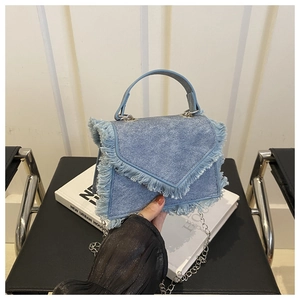 Detail of light blue denim crossbody bag featuring trendy long fringe and silver chain strap