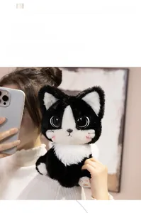 Close-up of cute plush black cat doll held by a person in a cozy indoor setting
