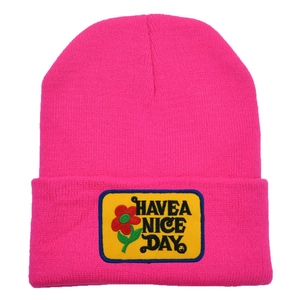 Close-up of pink knit beanie featuring a yellow Have a Nice Day floral patch embroidery