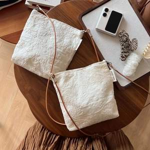 Detail view of cotton linen crossbody bags with exquisite floral embroidery on a wooden table