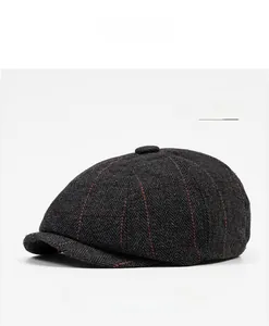 Detail of dark grey herringbone newsboy cap with orange plaid lines and top fabric button
