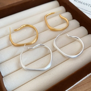 Detailed view of matte irregular gold and silver hoop earrings on a velvet display