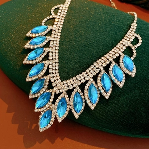 Detailed view of luxury blue teardrop necklace on green velvet display cushion