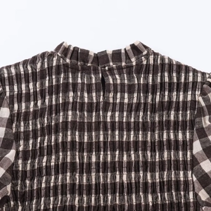 Detail of smocked honeycomb plaid texture and turtleneck design on this stylish blouse