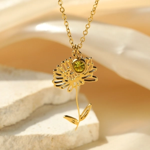 Close-up of 18k gold-plated flower pendant with a green gemstone on a cross chain