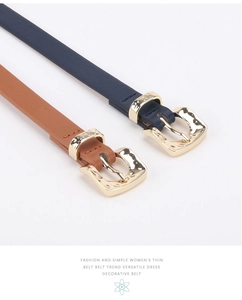 Detail of dark blue and brown thin leather belts with hammered gold metal buckles