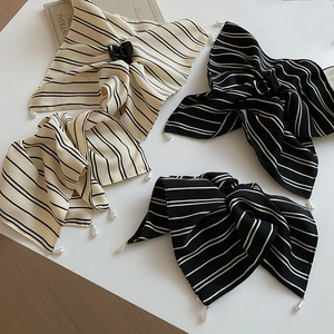 Détail de pinces à cheveux à rayures avec nœud et perles en tons crème et noir élégants