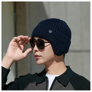 Detail of navy knit ear protection hat with rib texture and metal logo on a model