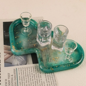 Emerald marble resin tray with gold foil accents and glass cups on a newspaper