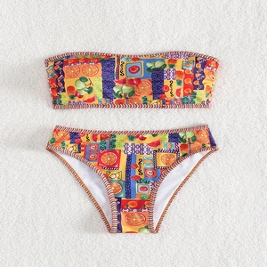 Flachbild-Detail eines Bikini-Sets mit buntem tropischem Frucht-Fliesenmuster auf weißem Teppich