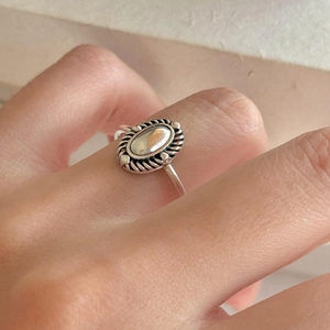 Close-up of a 925 sterling silver oval ring with twisted rope edge on a model hand